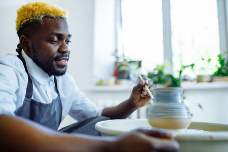 mixed race man making a vase in pottery studioの写真素材