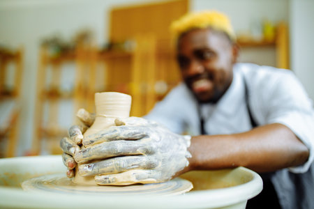 mixed race man making a vase in pottery studioの写真素材
