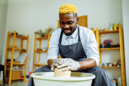 mixed race man making a vase in pottery studioの写真素材