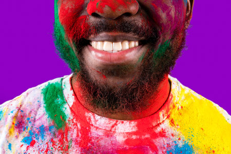 Afro american man celebrate holi festival in violet studio backgroundの写真素材