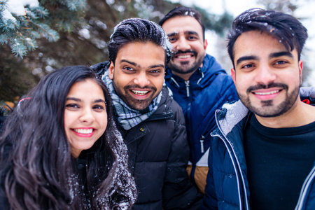 group of four indian having fun playing in snow outdoors spending Chrisymas holidays