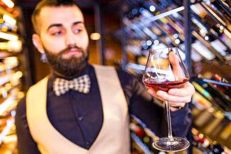 happy successful male winemaker is tasting a flavor and checking red wine qualityの写真素材