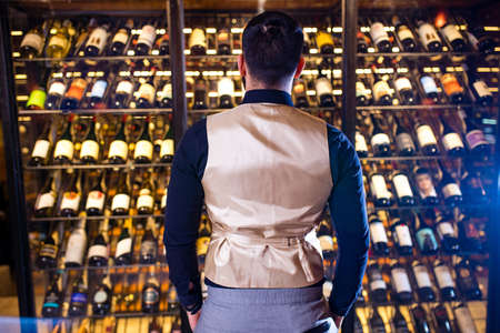 happy successful male winemaker is tasting a flavor and checking red wine qualityの写真素材