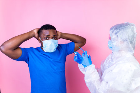 African american man scientist in PPE suite uniform showing medicine liquid vaccine vial bottle...