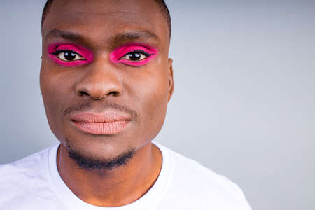 afro american man in white t-shirt casual style with pink eyeshadow and lipstick crossdressing in fashion show studio backgroundの写真素材