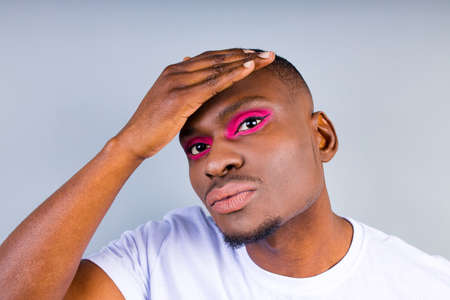 afro american man in white t-shirt casual style with pink eyeshadow and lipstick crossdressing in...