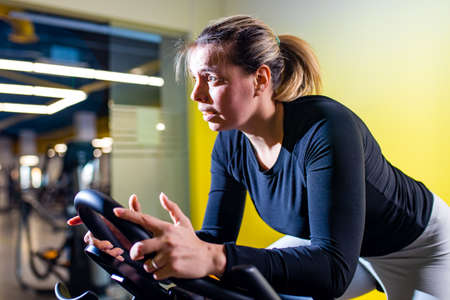 woman cycling on the machine trainer exercising in the gymの写真素材