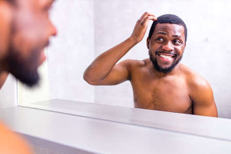 good-looking brazilian man smiling morning cheer up himself looking at mirror in bathroomの写真素材