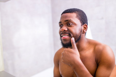 good-looking brazilian man smiling morning cheer up himself looking at mirror in bathroomの写真素材