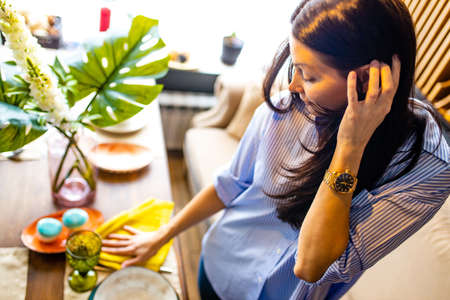 a woman reading to date setting a table in her houseの写真素材