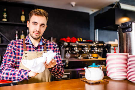 Stylish brutal barman is cleaning the glass with a napkinの写真素材