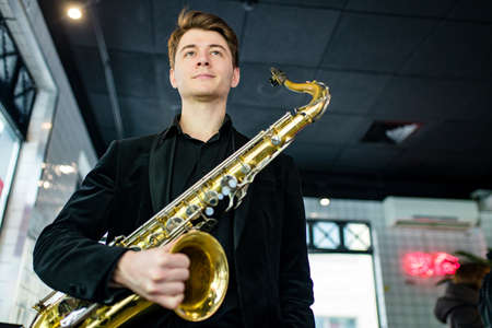 saxophone in hands close-up man in black outfitの写真素材