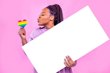 latino spain holding blank empty banner kissing a rainbow heart in pink studioの写真素材