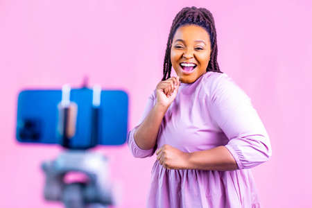 hispanic woman with cool dreadlocks pigtails wear pink dress in studio chatting with her subscribers...