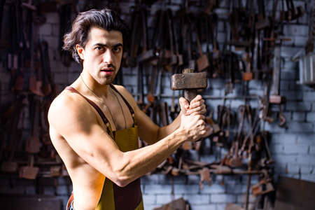 italian brunette man blacksmith working in the workshopの写真素材