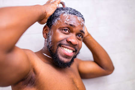 good-looking brazilian man smiling morning cheer up himself looking at mirror in bathroomの写真素材