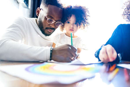 cute curly afro hair girl drawing with her dad parents positive education toleranceの写真素材