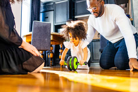 african mulatto family working out at home with children exercises with Ab Wheel absの写真素材