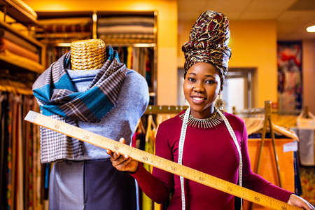 tanzanian woman with snake print turban over hear working in fabrics shop with rulerの写真素材