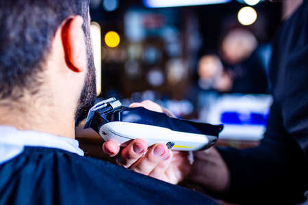Hairstylist cutting hair of male customer at barber shop