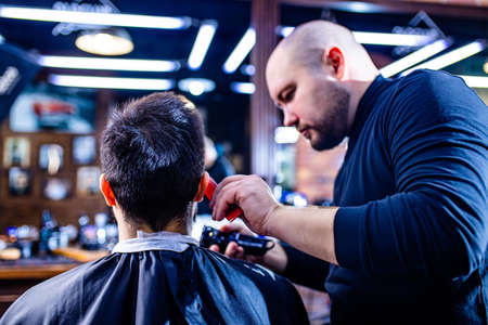 Hairstylist cutting hair of male customer at barber shop