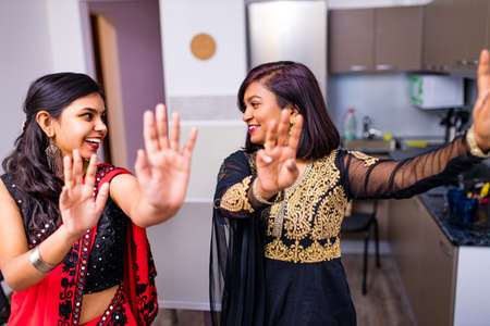 happy indian sisters are dancing together in new light apartment with design repair moving concept houseの写真素材