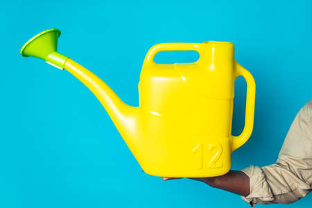 latino spain man in black apron holding yellow watering can in blue studioの写真素材