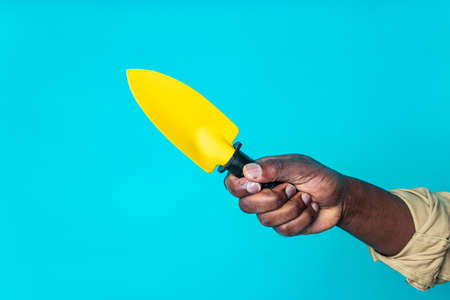 brazilian gardener man holding garden items in studio blue backgroundの写真素材