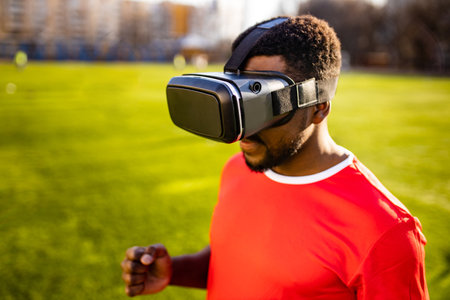 happy man in virtual reality glasses in football field background is blurred concept of virtual reality outdoors summer sunny dayの写真素材