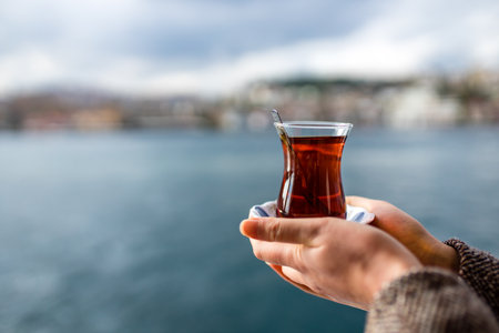 woman drinking Turkish tea in the front, bosphorus bay in the backgroundの写真素材
