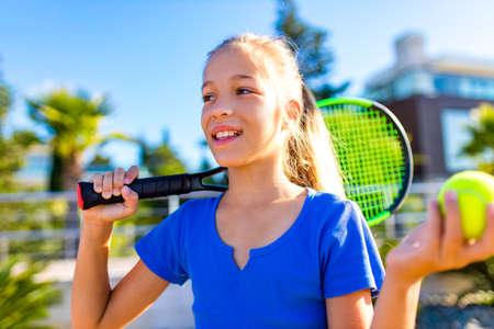 Portrait of a young girl with a tennis racket and ball outdoors tropical backgroundの写真素材