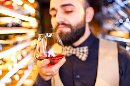 happy successful male winemaker is tasting a flavor and checking red wine qualityの写真素材