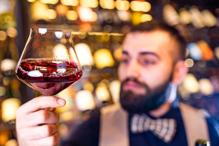 happy successful male winemaker is tasting a flavor and checking red wine qualityの写真素材