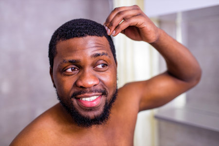 good-looking brazilian man smiling morning cheer up himself looking at mirror in bathroomの写真素材