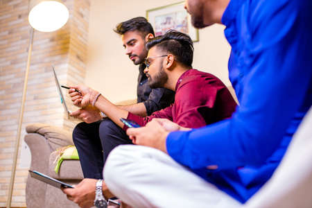 friends from india looking something interesting on laptop in livingroomの写真素材