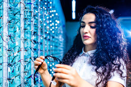 eastern ethnic woman in white medical coat robe selling glasses in optical store