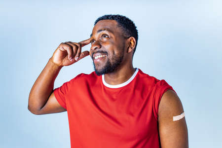 vaccinated mixed race showing an adhesive bandage on shoulder after injection studio background