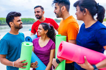 mixed race four people talking sfter training in a yoga class outside in park urban