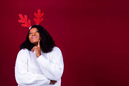 Joyful brazil charming woman in toy deer horns holding red ball gift box while at cozy room