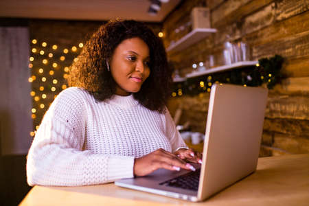 brazilian woman connection with her family online in evening room with Garlands lights backgroindの写真素材