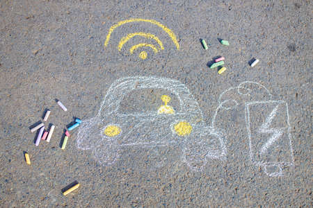 Little girl with creative craft hobby drawing electro on the asphalt with chalk car environment, eco friendly, save energy in park at summer dayの写真素材