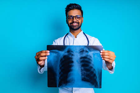indian doctor showing chest bone film x-ray image in blue studio baclgroundの写真素材