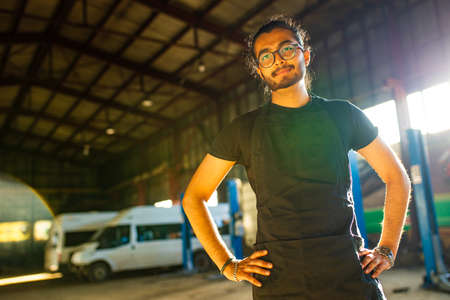 Auto mechanic standing in his workshop in sunset light background