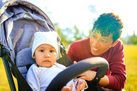 mixed race family happy father with little girl in stroller at summer park