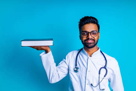 latin american student male in white coat and eyes glasses in studio blue backgroundの写真素材