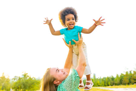 little girl with cool afro curly hair having fun together with mom outdorの写真素材