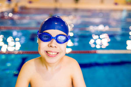 Disabled boy with Down syndrome in swimming cap with goggles