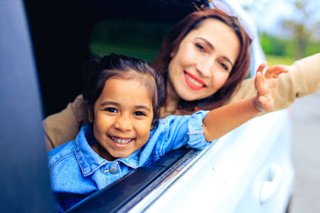happy child girl with mother in car going on a summer vacation tripの写真素材