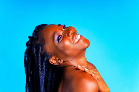 african american woman with gorgeus bright color make up feels proud and self confident in blue wall studio backgroundの写真素材
