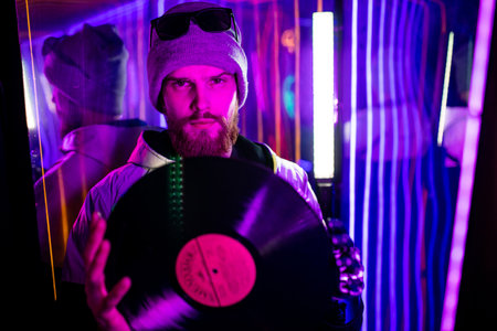 robotics dj man with metal hand nostalgia about past time in neon studio feeling loneliness hold disc for vinyl recordの写真素材